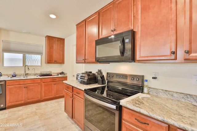 kitchen with stainless steel appliances, sink, light tile flooring, and light stone counters