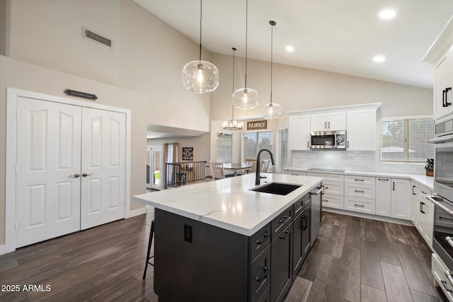 19002 N 25th Pl, Phoenix, AZ 85050 - kitchen with stainless steel appliances, white cabinetry, dark wood finished floors, a center island with sink, and high vaulted ceiling
