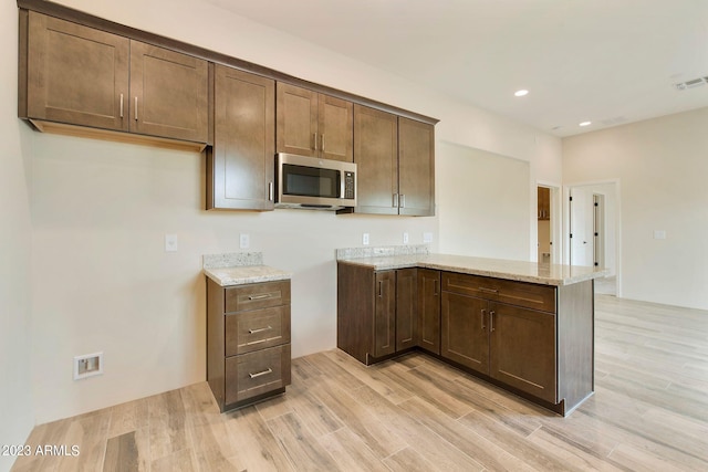 48111 N 7th Ave, New River, AZ 85087 - kitchen featuring dark brown cabinets, light hardwood / wood-style floors, light stone counters, and kitchen peninsula