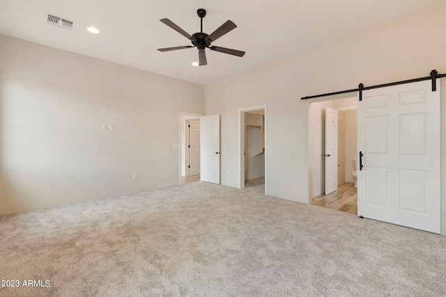 48111 N 7th Ave, New River, AZ 85087 - unfurnished bedroom with ceiling fan, a barn door, light colored carpet, and ensuite bath
