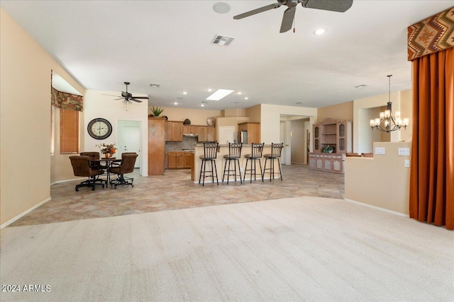 carpeted living room with ceiling fan with notable chandelier