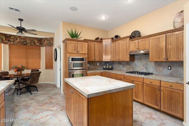 kitchen featuring a kitchen island, ceiling fan, tasteful backsplash, and appliances with stainless steel finishes