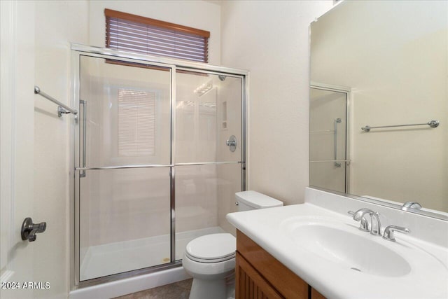 bathroom featuring vanity, a shower with shower door, and toilet