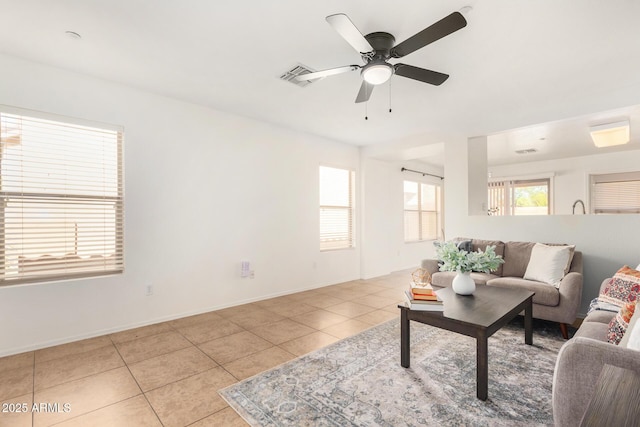 living room featuring light tile patterned floors, ceiling fan, visible vents, and baseboards