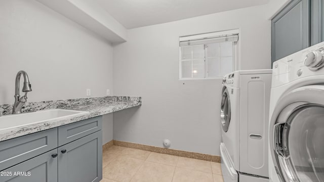laundry room with cabinet space, washer and dryer, baseboards, and light tile patterned floors