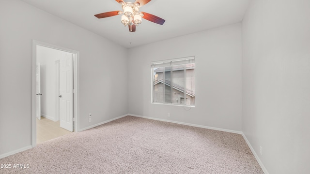carpeted spare room with a ceiling fan and baseboards