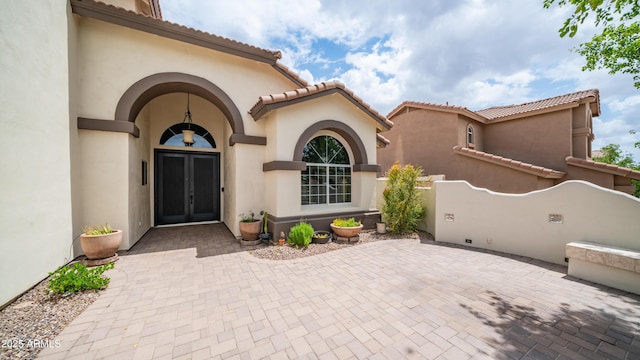 doorway to property featuring stucco siding and a tiled roof