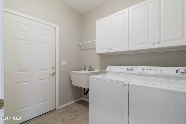 laundry area with cabinets, light tile patterned floors, sink, and washing machine and clothes dryer