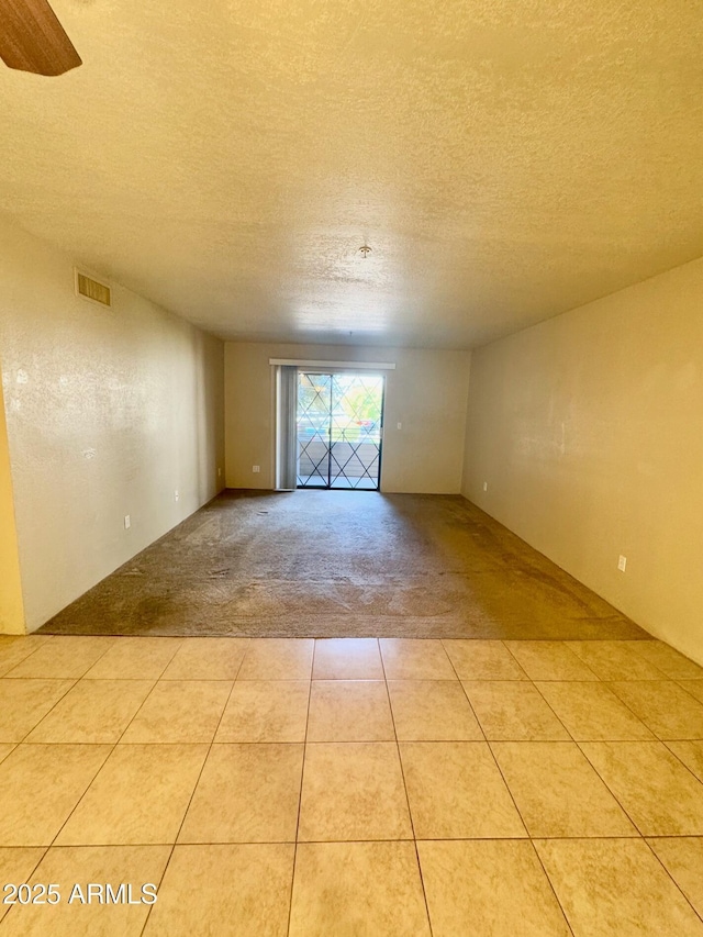 empty room with light colored carpet and a textured ceiling