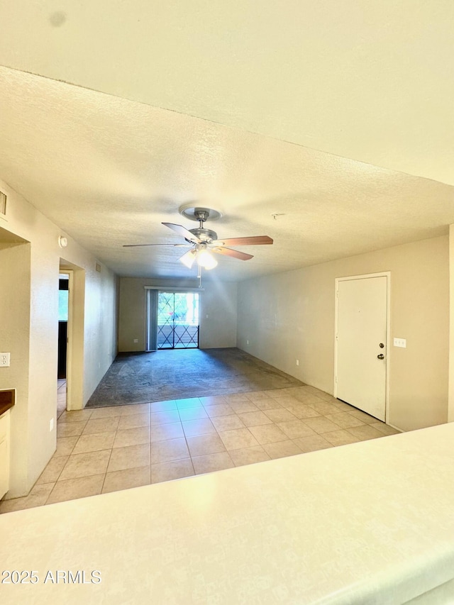 spare room with ceiling fan, a textured ceiling, and light tile patterned floors