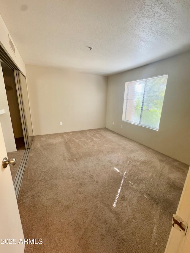 empty room with carpet flooring and a textured ceiling