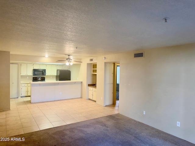 interior space with fridge, light colored carpet, white cabinets, and kitchen peninsula