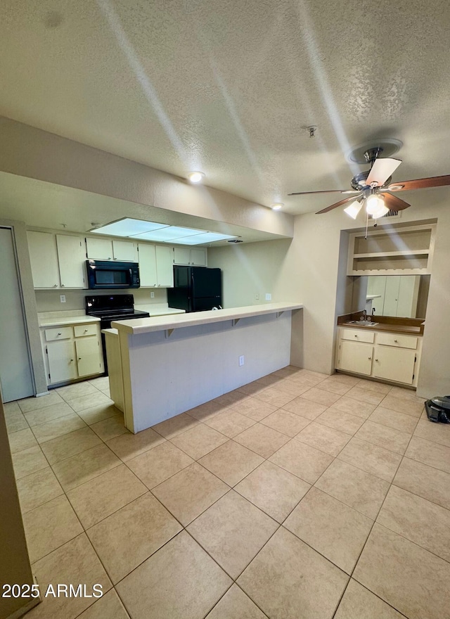 kitchen with black appliances, kitchen peninsula, white cabinets, and light tile patterned flooring