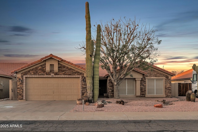 ranch-style home featuring a tiled roof, concrete driveway, stucco siding, stone siding, and an attached garage