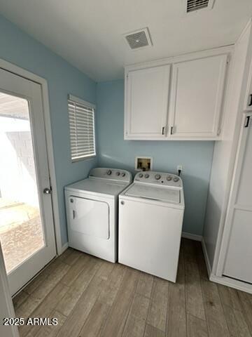 laundry room with cabinets, a wealth of natural light, light hardwood / wood-style floors, and washing machine and clothes dryer