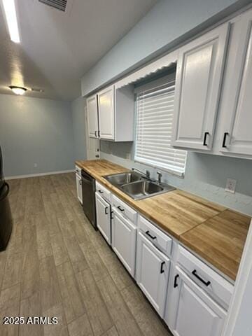 kitchen featuring butcher block countertops, black dishwasher, sink, and white cabinets