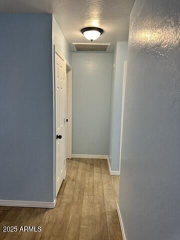 corridor with light hardwood / wood-style flooring and a textured ceiling