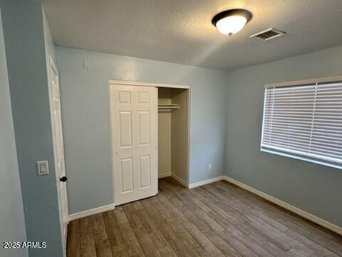 unfurnished bedroom featuring a closet, wood-type flooring, and a textured ceiling