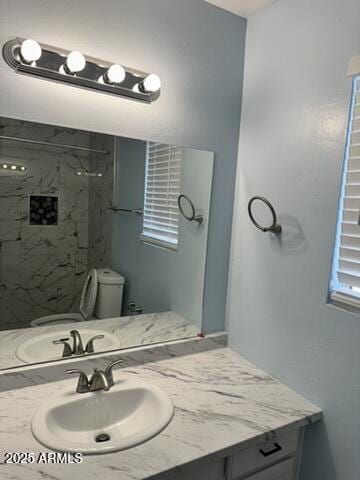 bathroom with vanity, a tile shower, and toilet