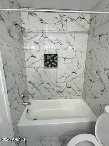 bathroom featuring toilet and tiled shower / bath