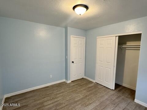 unfurnished bedroom with hardwood / wood-style flooring, a closet, and a textured ceiling