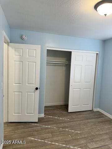 unfurnished bedroom with dark hardwood / wood-style floors and a closet