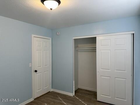 unfurnished bedroom with dark hardwood / wood-style floors and a closet