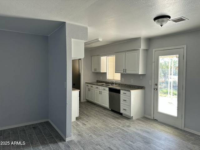 kitchen with white cabinetry, sink, stainless steel dishwasher, and a textured ceiling