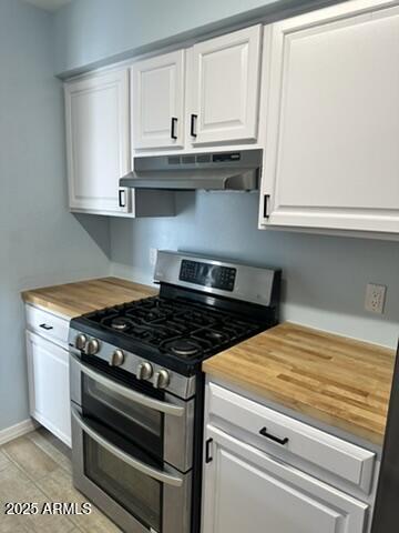 kitchen with range with two ovens, white cabinetry, and wooden counters