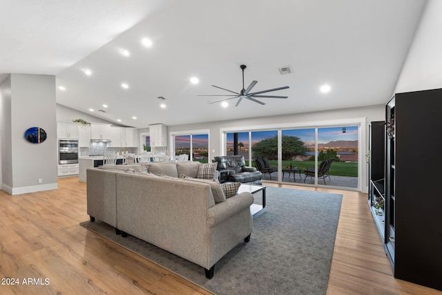 living room featuring ceiling fan, lofted ceiling, a wealth of natural light, and light wood-type flooring