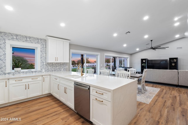 kitchen featuring kitchen peninsula, vaulted ceiling, sink, and stainless steel dishwasher