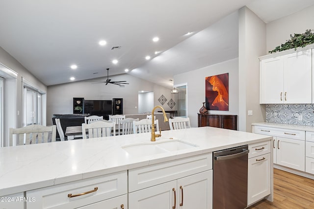 kitchen with light stone counters, white cabinets, lofted ceiling, and sink