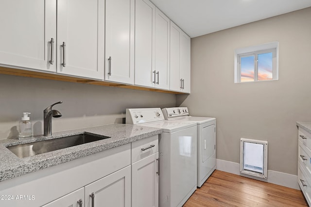 washroom with washer and dryer, cabinets, sink, and light wood-type flooring