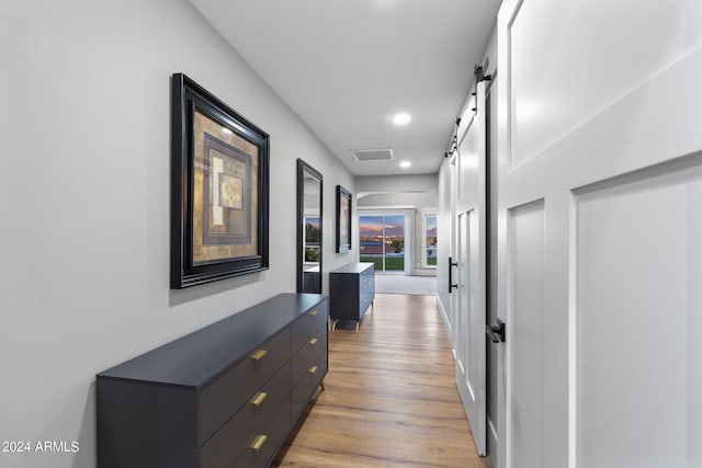 corridor featuring a barn door and light hardwood / wood-style floors