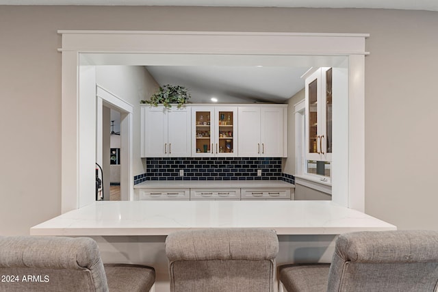 kitchen featuring a breakfast bar area, backsplash, and white cabinets