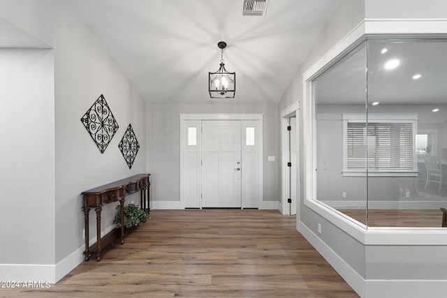 foyer with hardwood / wood-style flooring, lofted ceiling, and a chandelier