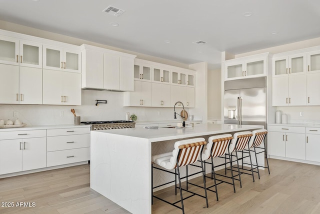 kitchen with white cabinetry, a kitchen island with sink, sink, and a kitchen bar