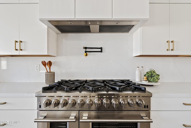 kitchen with white cabinetry, extractor fan, high end stainless steel range, and backsplash