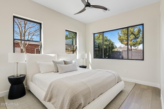 bedroom featuring multiple windows, wood-type flooring, and ceiling fan