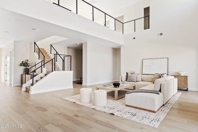 living room with a towering ceiling and light hardwood / wood-style floors