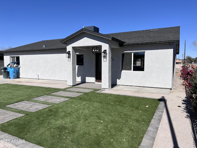 view of front of property featuring a patio, a front lawn, a shingled roof, and stucco siding