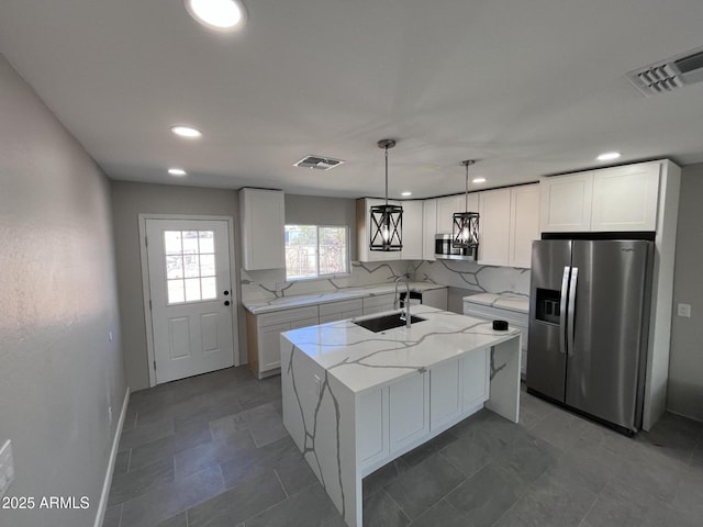 kitchen with appliances with stainless steel finishes, a center island, white cabinetry, and visible vents