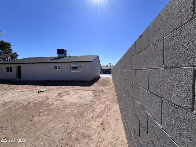 view of side of home with central AC and fence