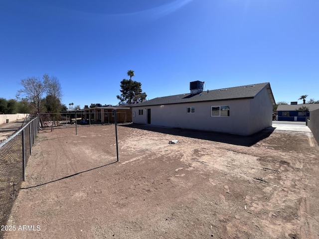 back of property with central AC unit, fence, and stucco siding