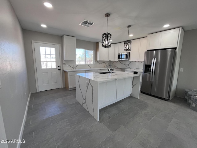 kitchen featuring hanging light fixtures, appliances with stainless steel finishes, white cabinets, a sink, and a kitchen island