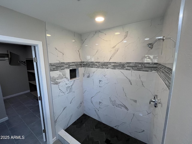 bathroom with a tile shower and a walk in closet