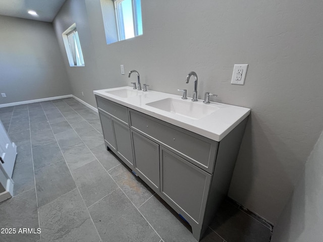 full bath with a sink, baseboards, and double vanity