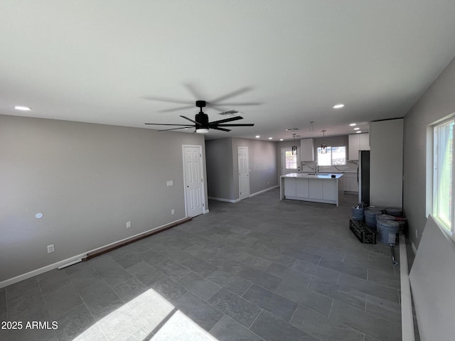 unfurnished living room with recessed lighting, a sink, a ceiling fan, and baseboards