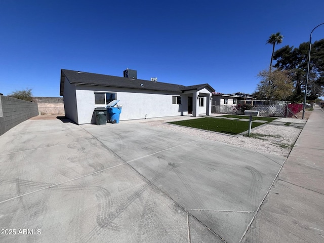 view of front facade with fence private yard, central AC unit, and stucco siding