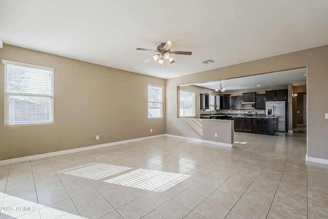 unfurnished living room with light tile patterned floors, baseboards, visible vents, and a wealth of natural light